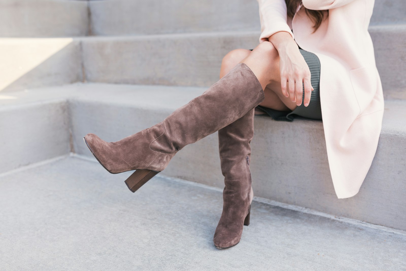 Vrouw in een donkere skinny jeans met hoge bruine suède laarzen op straat