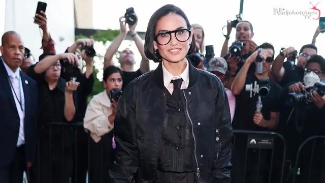 Demi Moore met een kinlange bob, grote bril en zwarte bomberjack voor de fotografen bij een show tijdens de modeweek in New York