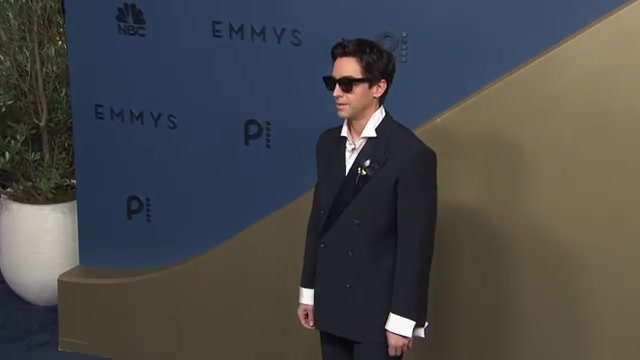 Donkerblauw dubbelrijs pak met zonnebril op de loper van de Emmy's 2026