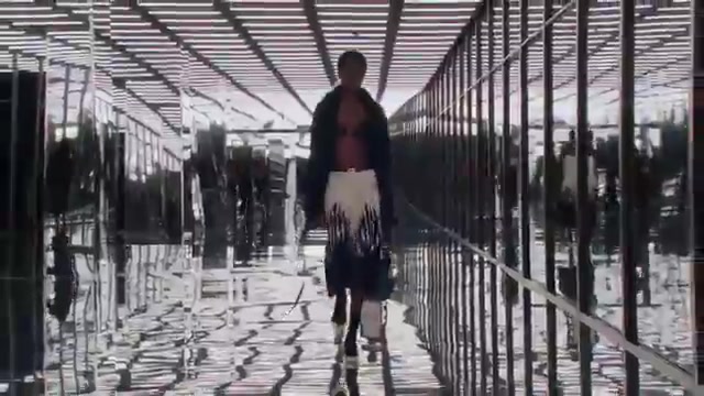 Model in een zwarte bh onder een open jas en een witte rok op de catwalk van Fendi voor lente 2027