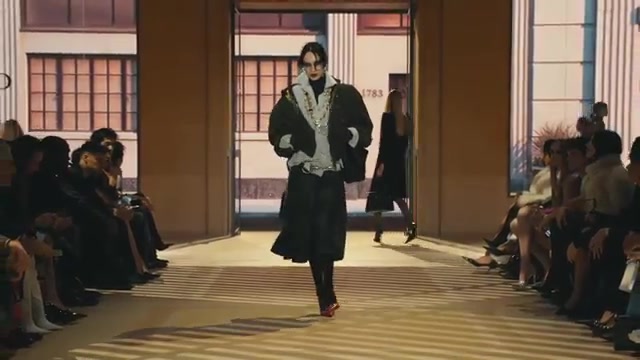 Model in een donkere jas op de catwalk van de Gucci Store Show in Milaan