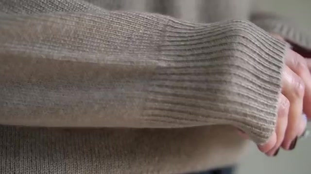 Close-up van de geribde mouwboord van een beige kasjmieren trui
