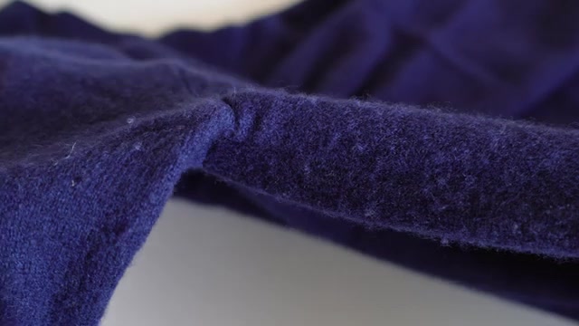 Pluisvorming op de mouw van een donkerblauwe kasjmieren trui, van dichtbij