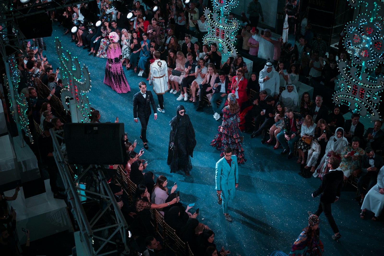 Model op de catwalk tijdens een modeshow, met publiek aan weerszijden