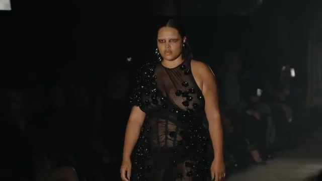 Model in een doorzichtige jurk met zwarte applicaties op de McQueen-catwalk in Londen