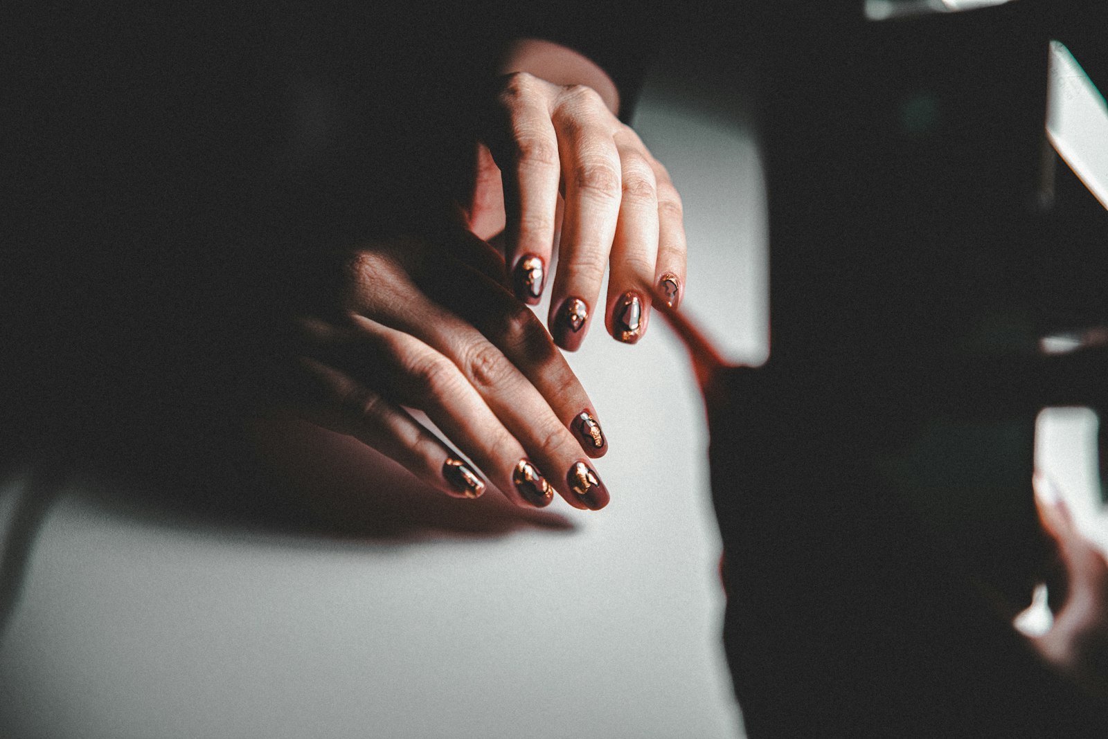 Hand met kort gelakte nagels in een diepe roodbruine tint