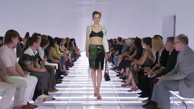 Model in een groene rok en zwarte bralette op de catwalk van Prada