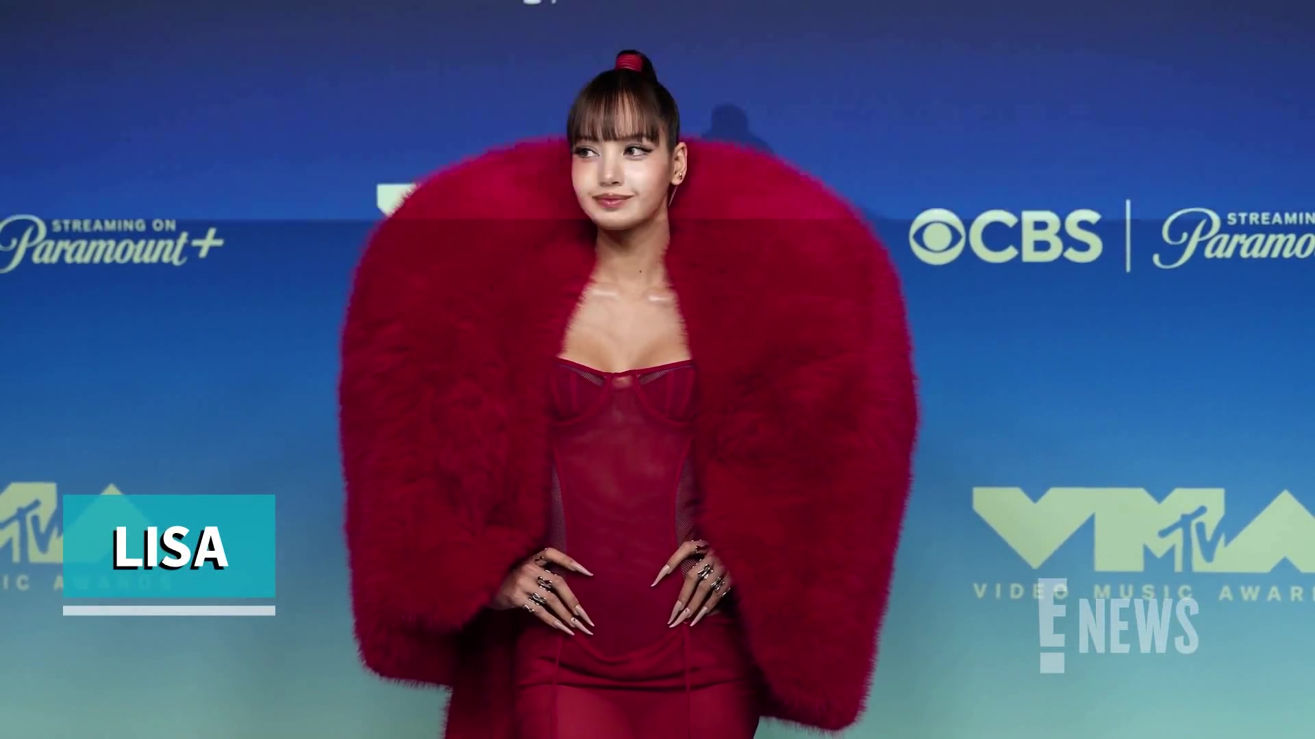Lisa in een rode jurk met grote rode cape op de rode loper van de MTV VMA's 2026
