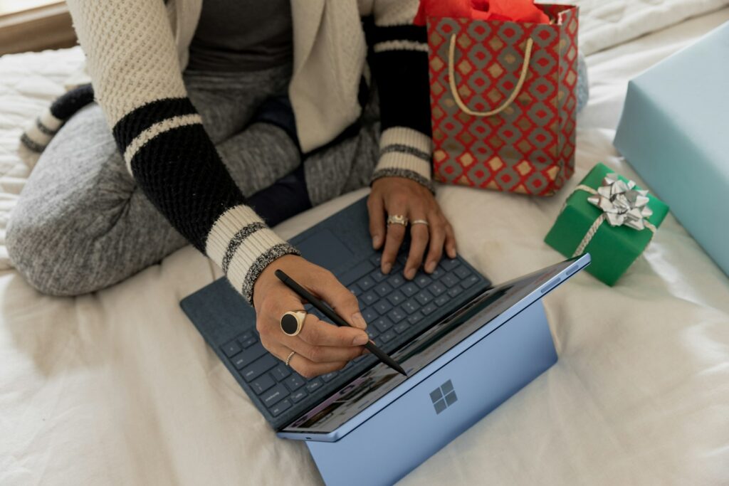 Vrouw bekijkt online aanbiedingen op haar laptop met pakketjes naast zich