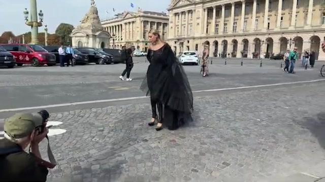 Gast in een zwarte outfit wordt gefotografeerd op de Place de la Concorde tijdens de modeweek in Parijs, uit een video van PichichiPixx