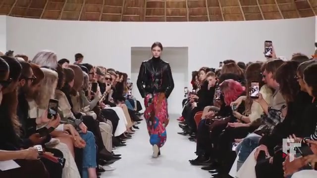 Model in een leren jack en bedrukte broek op de catwalk van Celine