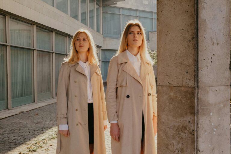 Vrouw in een korte beige trenchcoat met jeans op straat