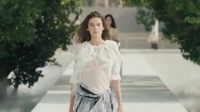 Model in een witte look op de mistige catwalk van Dior voor lente 2027 in de Tuilerieën