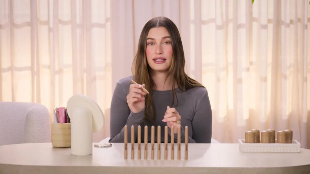 Hailey Bieber met lipproducten van Rhode aan tafel