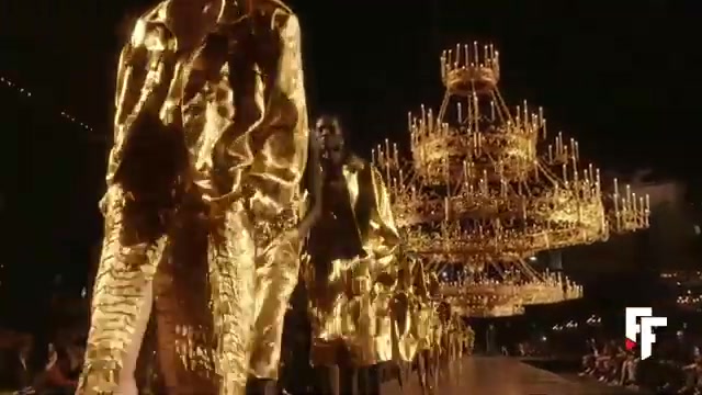 Modellen in gouden jassen onder kroonluchters op de catwalk van Saint Laurent voor lente 2027
