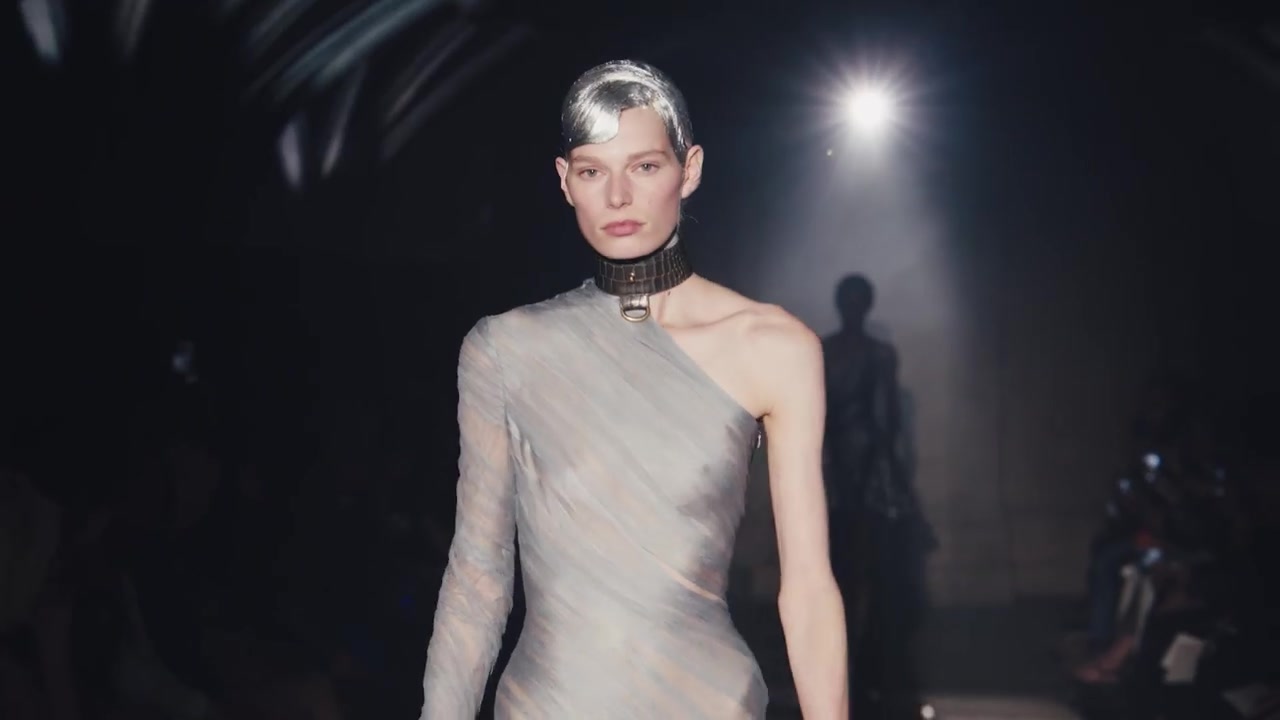 Model in een zilvergrijze asymmetrische jurk op de catwalk van McQueen lente zomer 2027