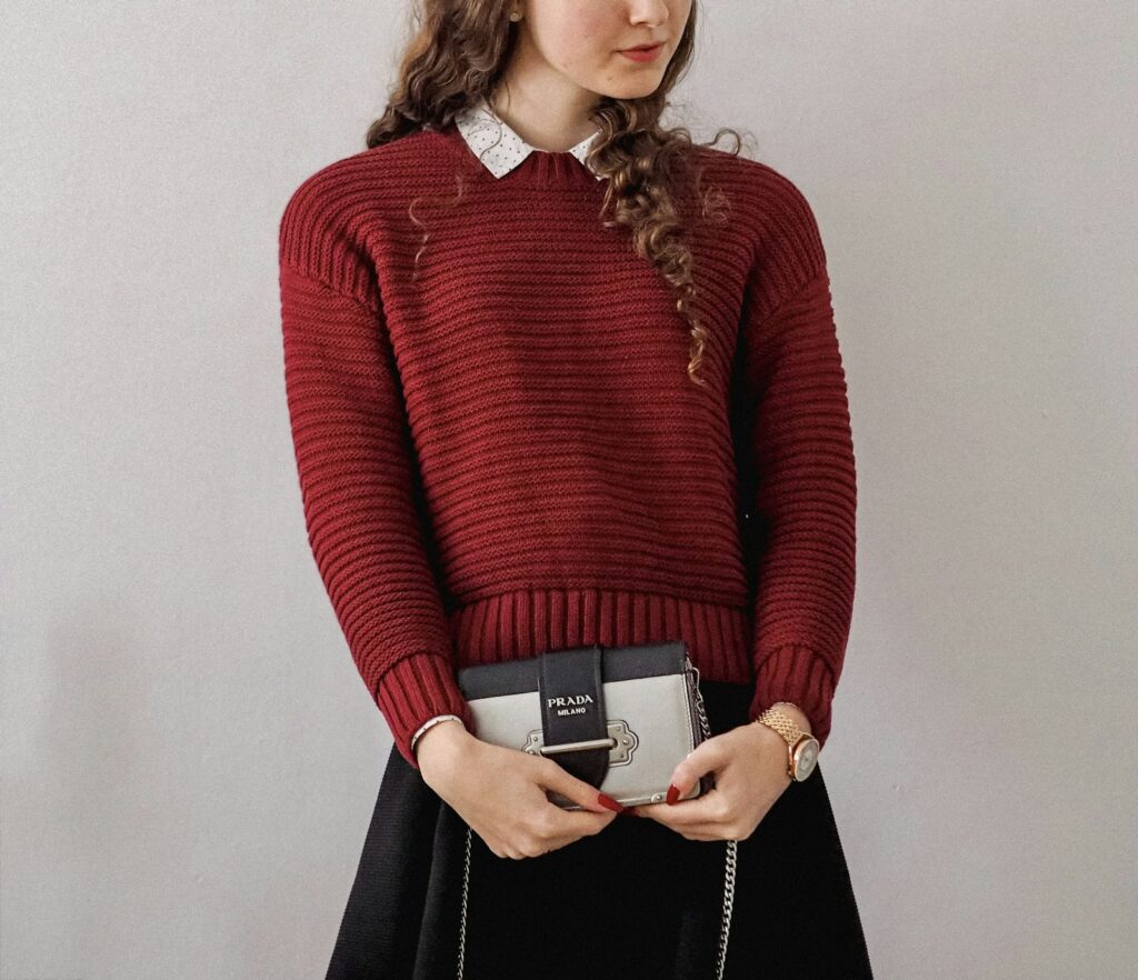 Vrouw in een gebreide trui met een diepe ronde hals over een wit overhemd