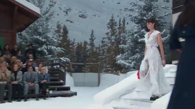 Model in een witte jurk op de besneeuwde catwalk van de Chanel-show herfst-winter 2019/20 in het Grand Palais, uit een video van Chanel